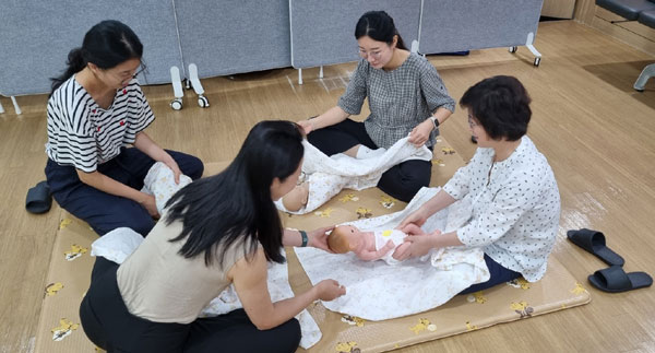 송파산모건강증진센터가 임신·출산 친화적 환경을 조성하기 위해 임산부 체험존을 운영하고 있다. 사진은 예비엄마가 신생아 모형을 활용해 아기싸기를 실습하는 모습.